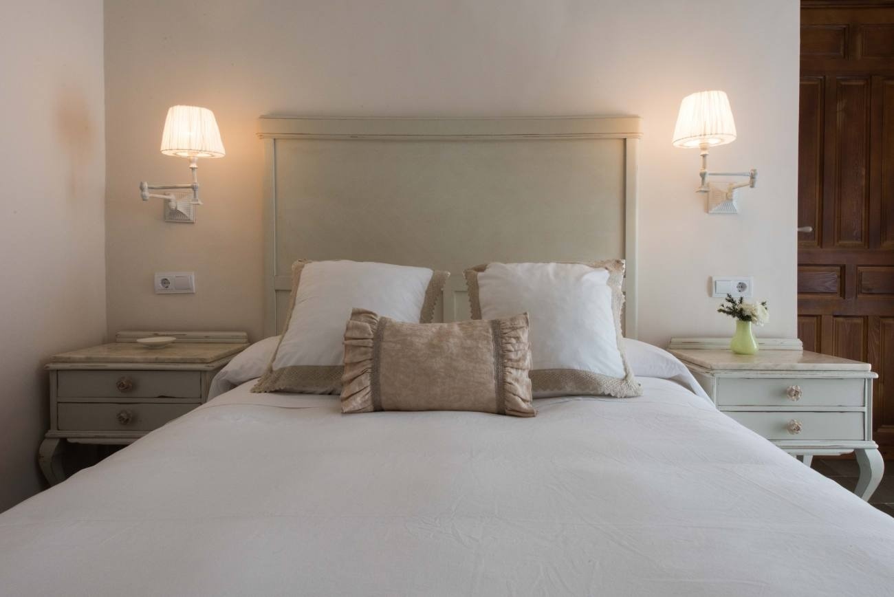 a bed with white sheets and pillows in a bedroom