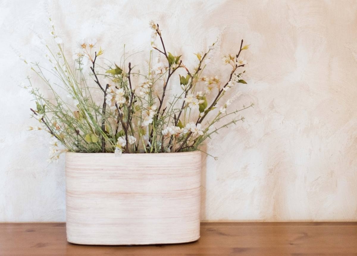 un jarrón de madera con flores blancas en él