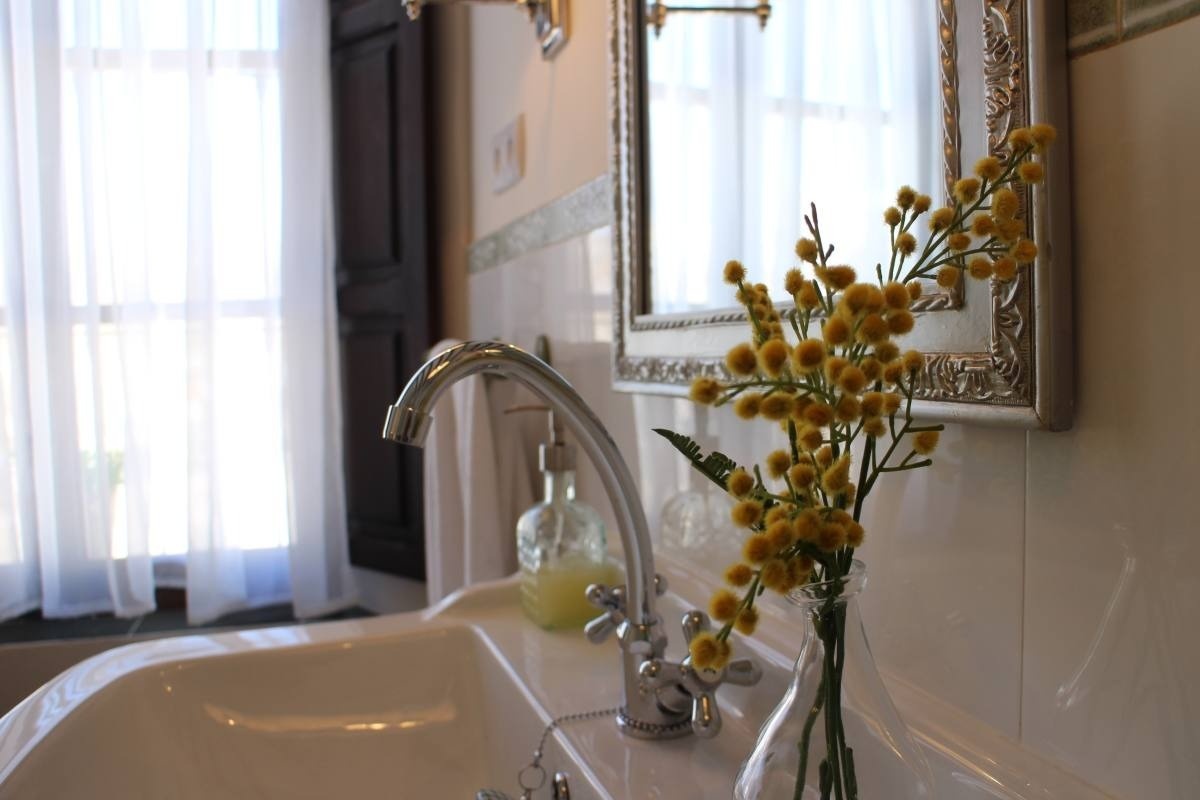 a bathroom sink with a vase of yellow flowers next to it