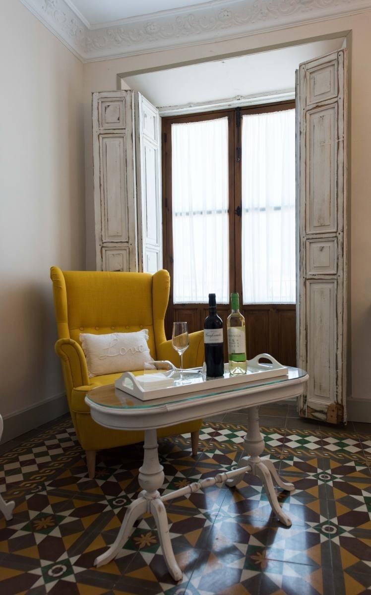 una silla amarilla y una mesa con una botella de vino encima