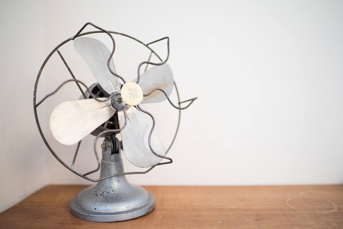 un ventilador antiguo está sobre una mesa de madera