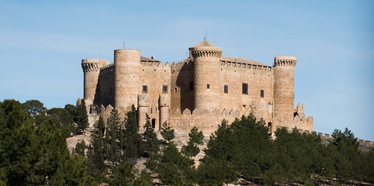 un castillo en la cima de una colina rodeado de árboles