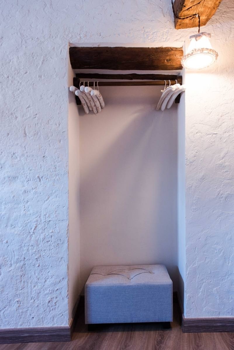 a closet with clothes hanging on a wooden rack