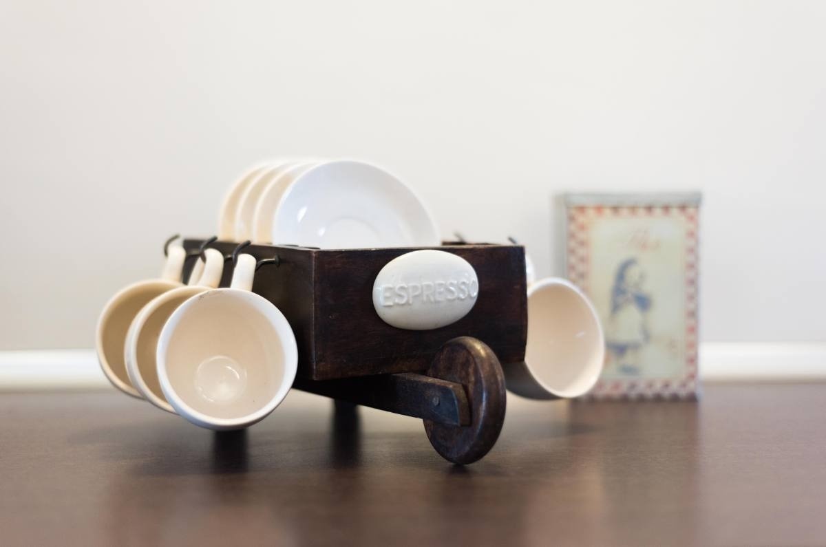 un carrito de madera con tazas de café y platillos y la palabra espresso encima