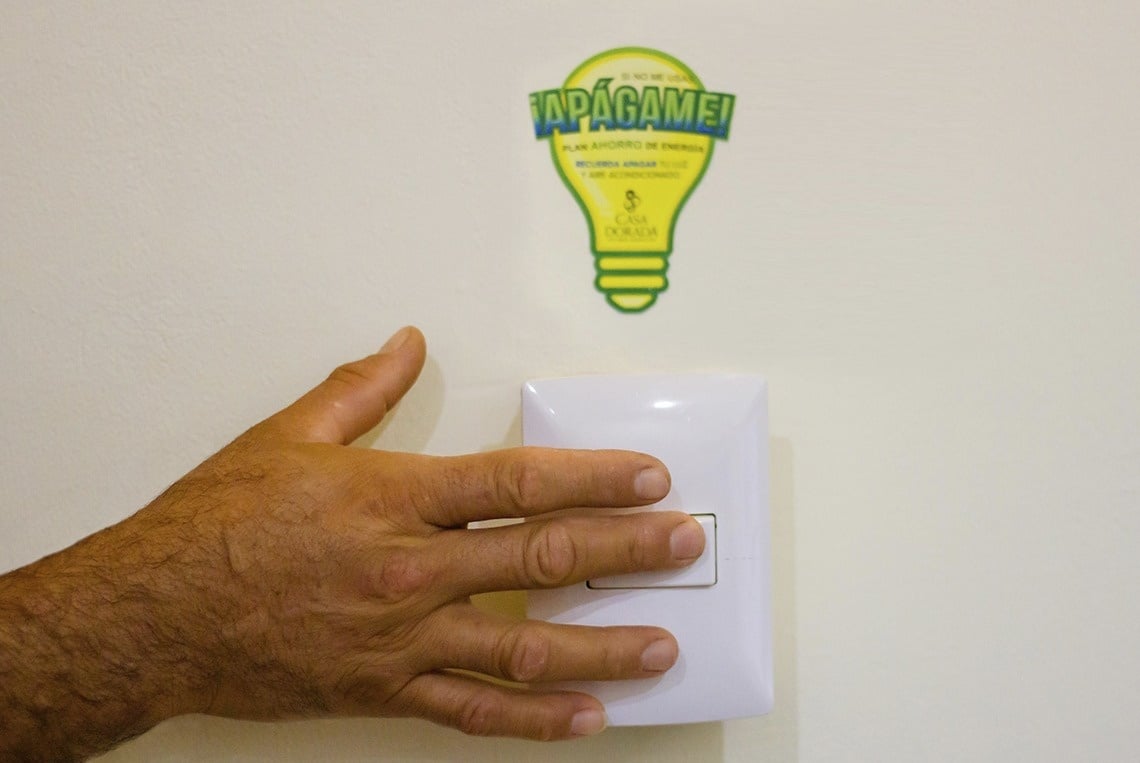 a hand is pressing a light switch next to a sticker that says tapagamei