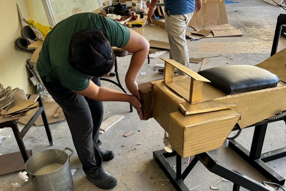 a man in a green shirt is working on a piece of cardboard