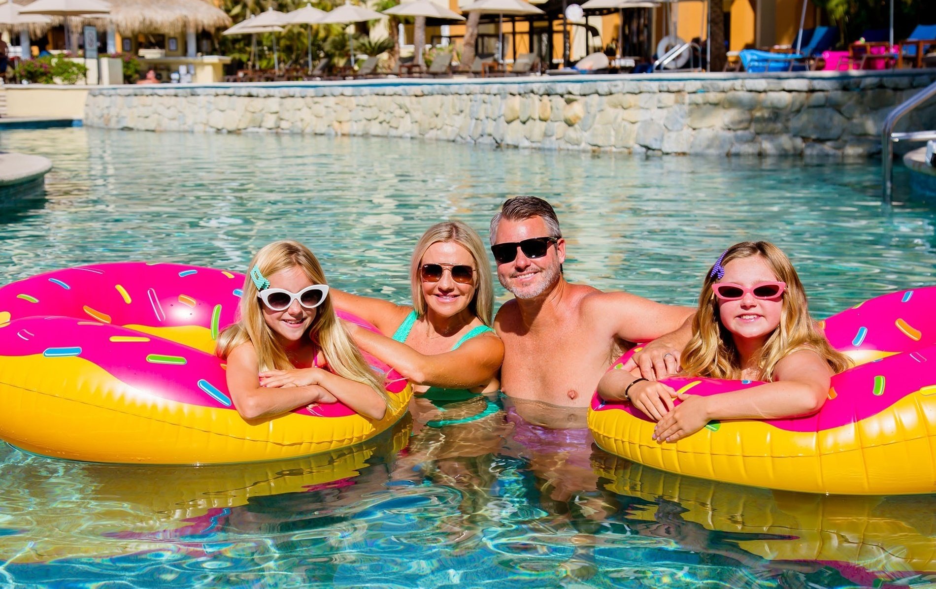 eine Familie schwimmt in einem Pool mit aufblasbaren Donuts
