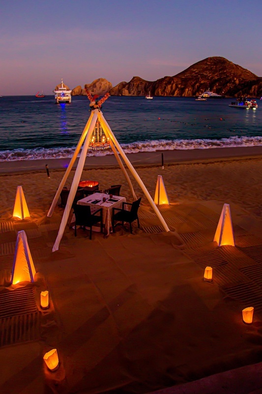 a teepee is set up on the beach with candles