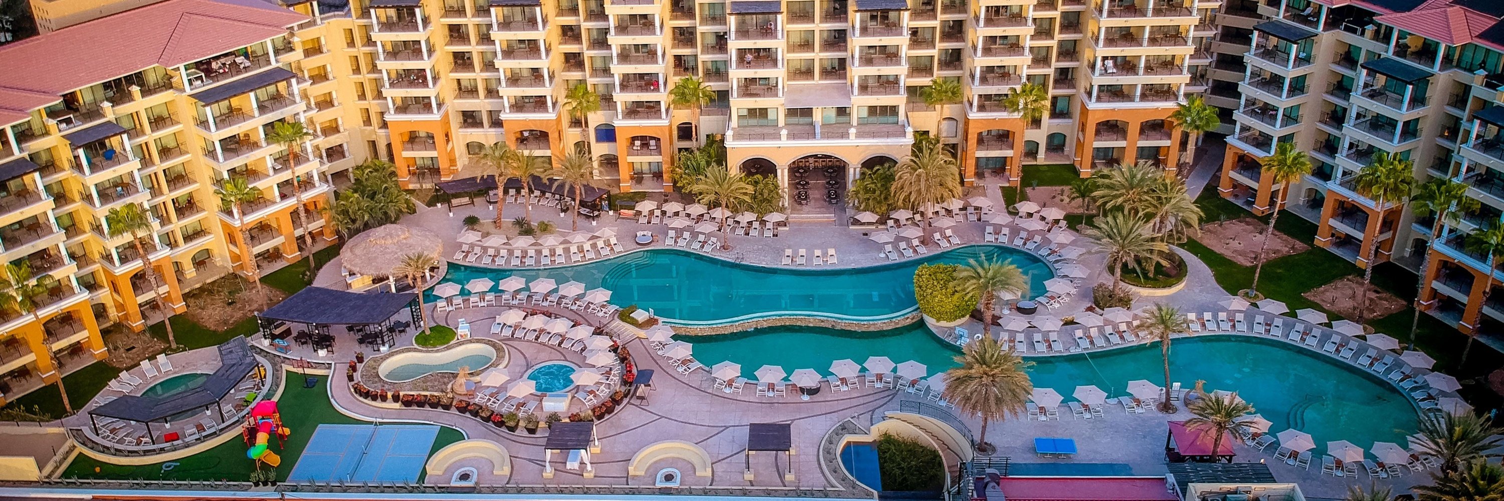 una vista aérea de un gran complejo de hoteles con piscinas y sombrillas