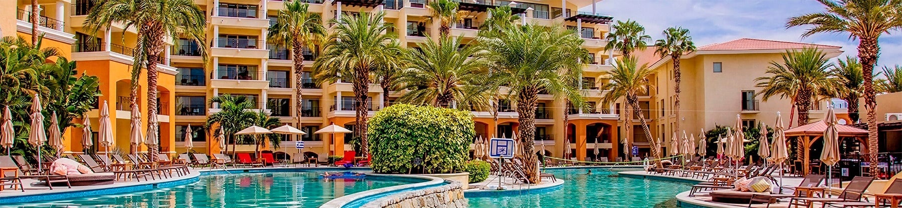 Complexe Casa Dorada avec piscine lagon, chaises longues et végétation luxuriante sous le soleil.