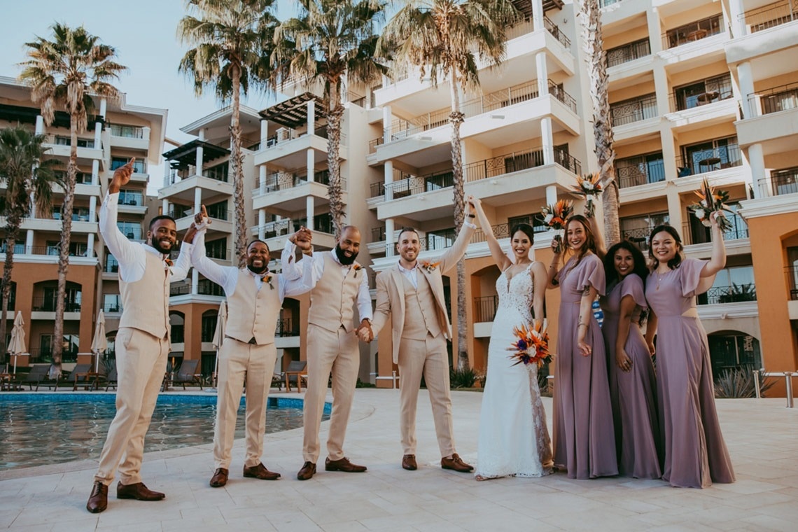 a bride and groom pose with their wedding party in front of a building