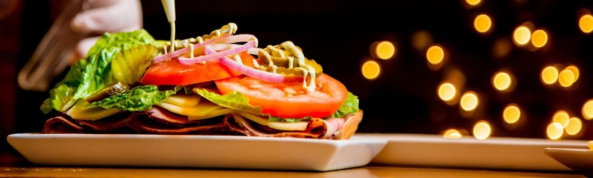 Sándwich gourmet fresco con lechuga, tomate, cebolla, carne y queso en restaurante de hotel. Cena o servicio a la habitación.