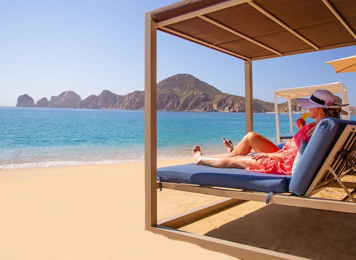 dos mujeres están sentadas en sillas en la playa y miran el océano