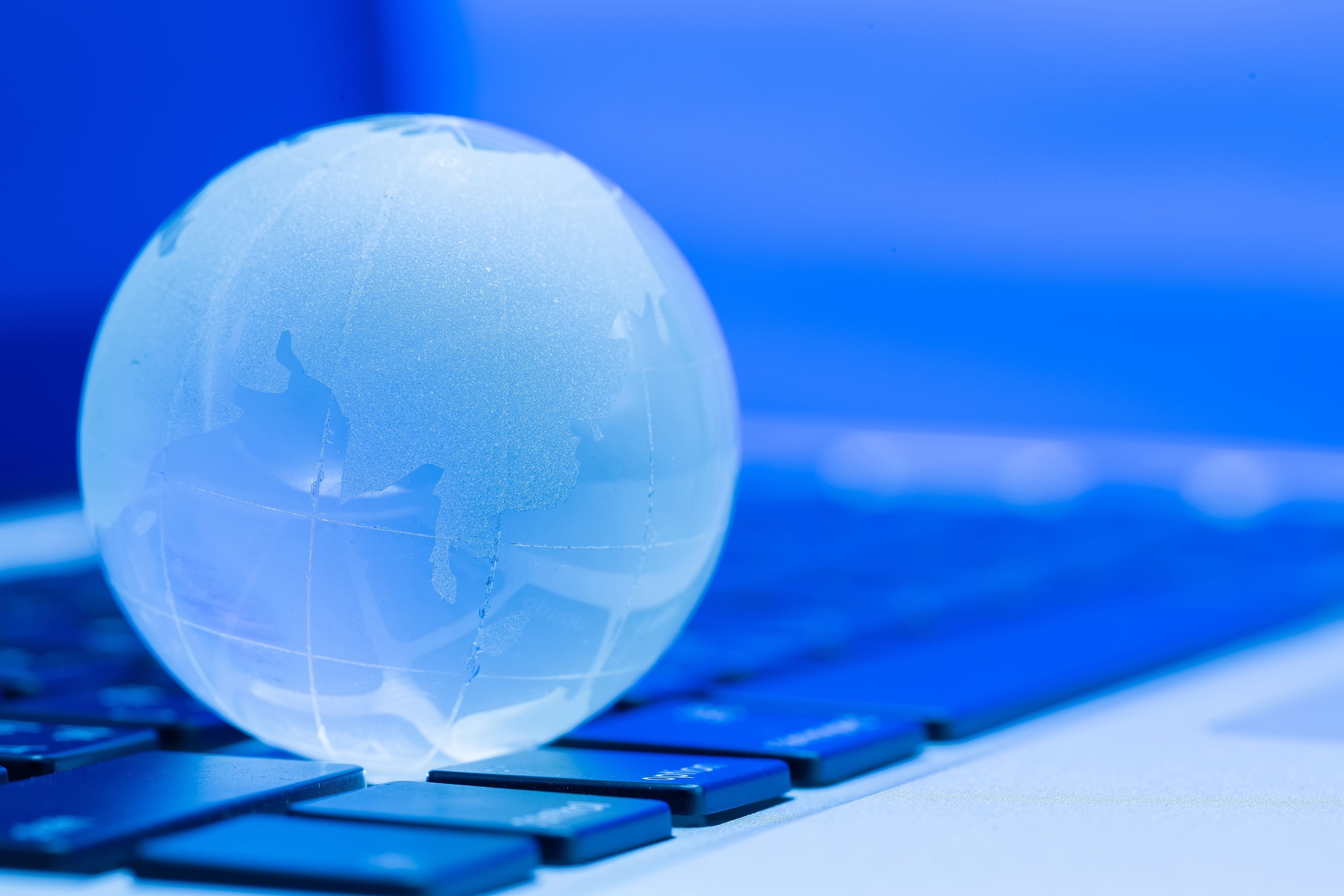 a globe sits on top of a laptop keyboard