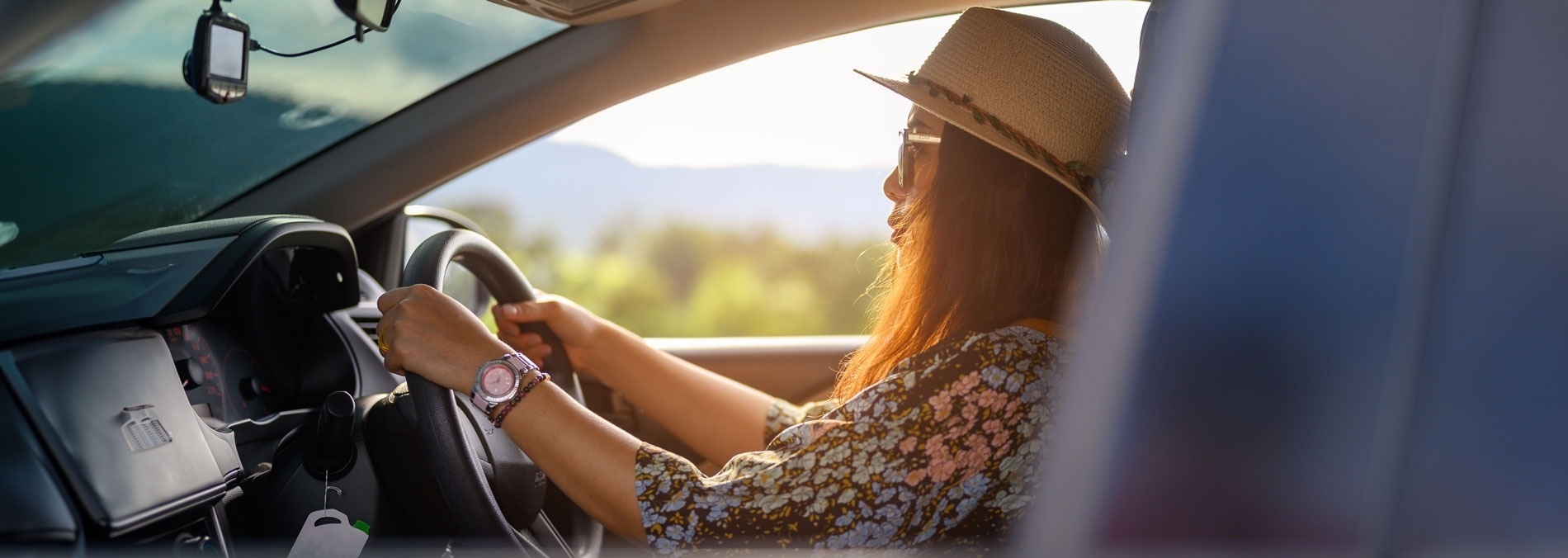Eine Frau fährt ein Auto und trägt einen Hut