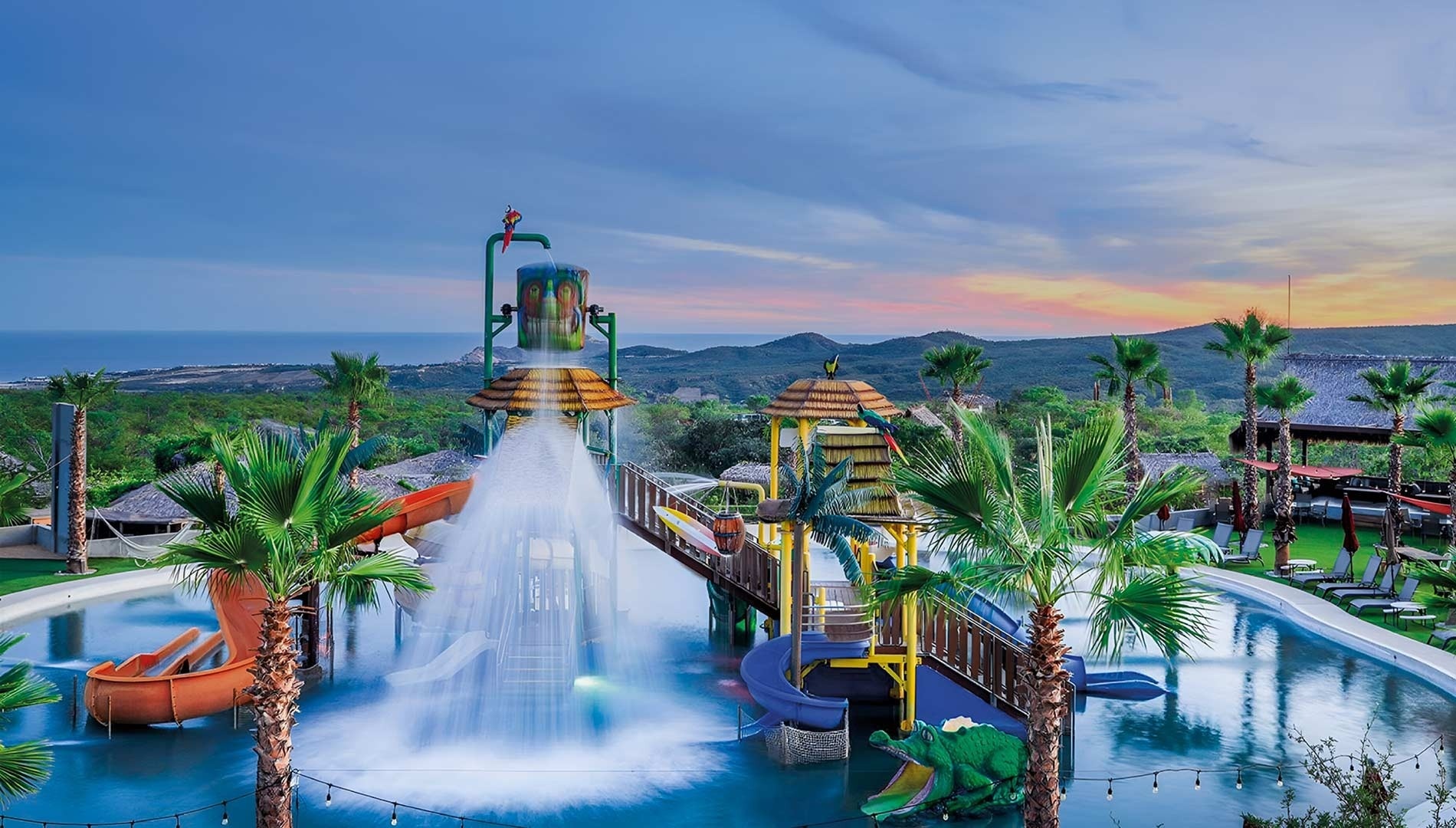a water park with palm trees and mountains in the background