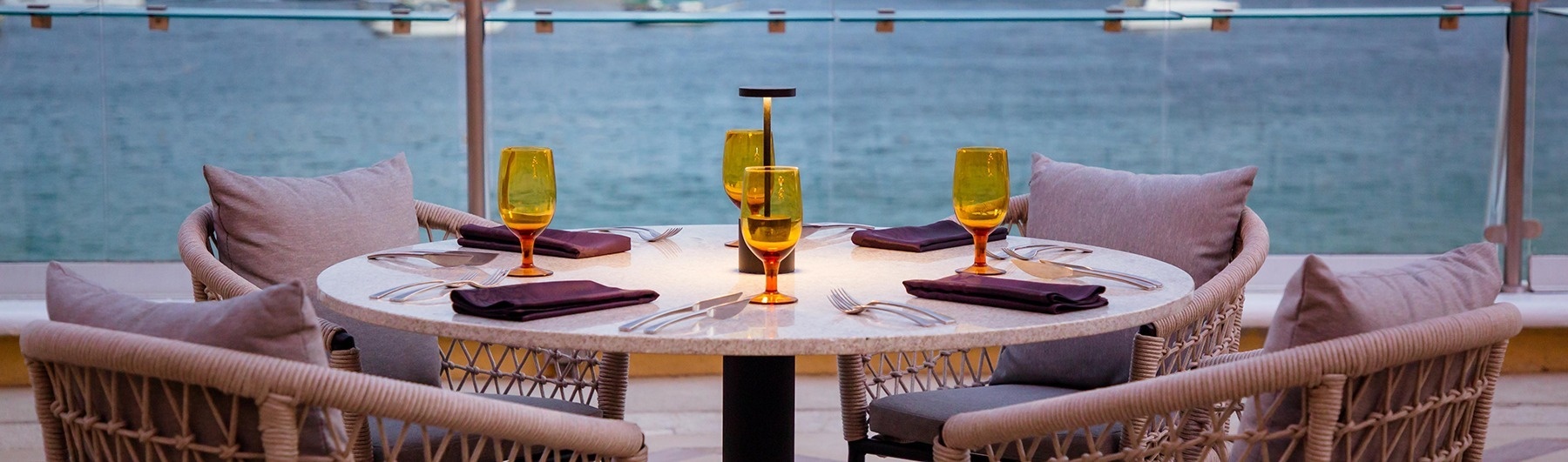une table avec des verres et des couverts à côté d' un balcon avec vue sur l' océan