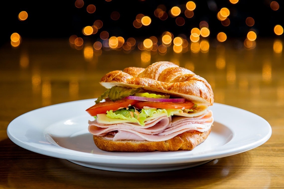 a ham and cheese sandwich on a croissant on a white plate