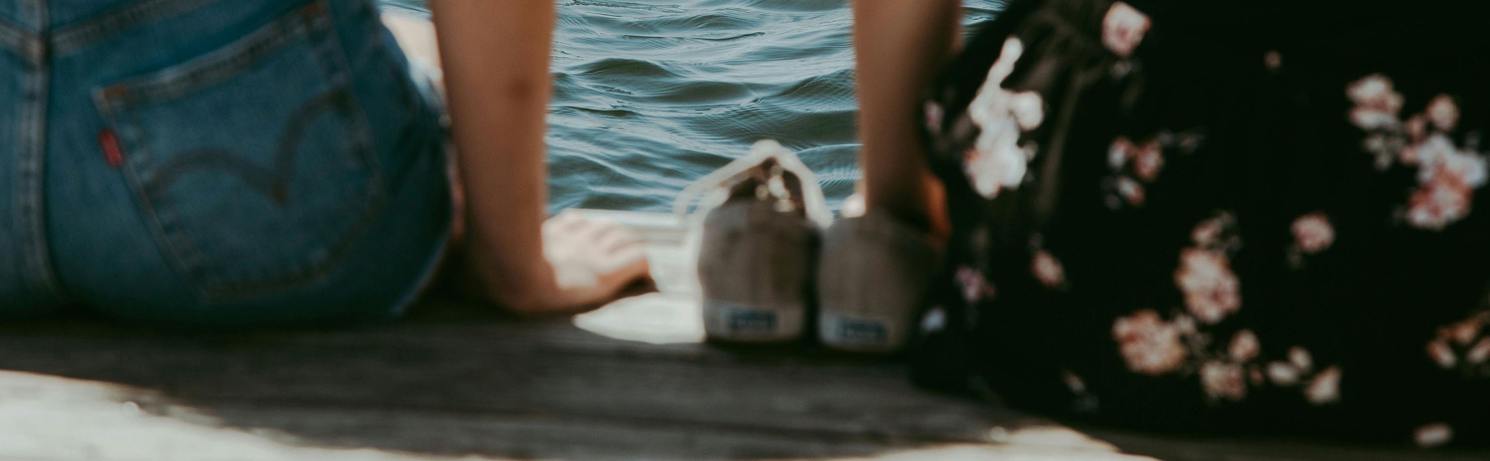 dos mujeres están sentadas en la playa con los pies en el agua