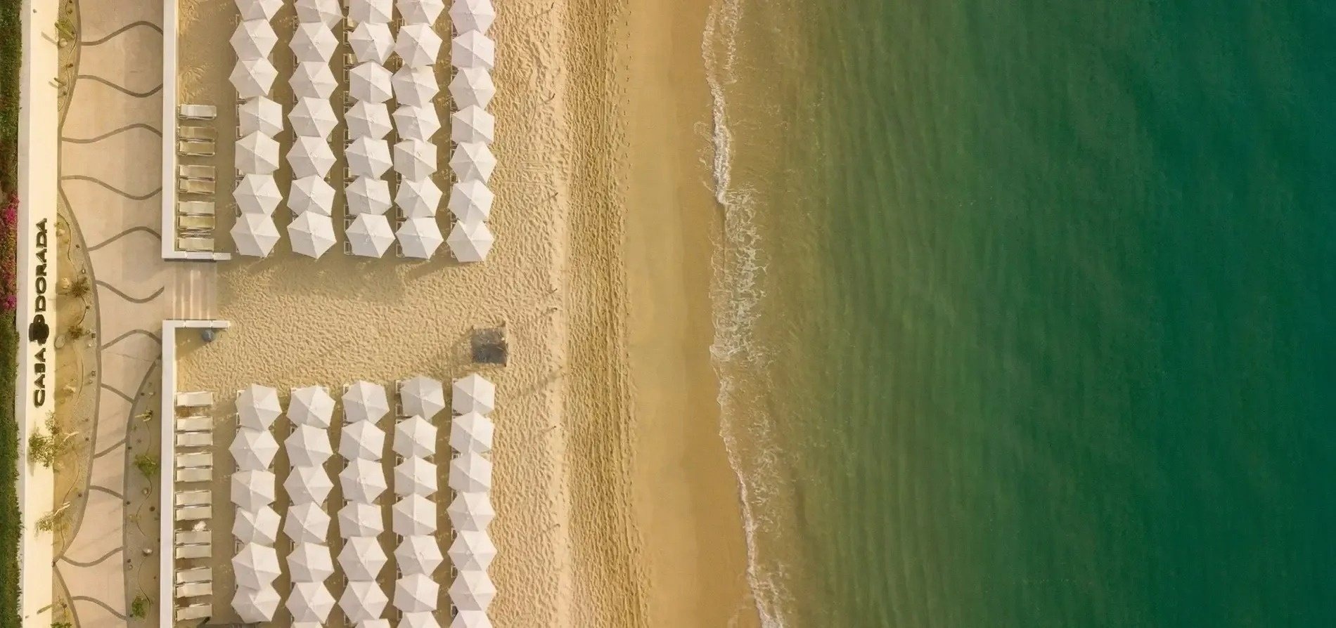 an aerial view of a beach with white umbrellas and chairs