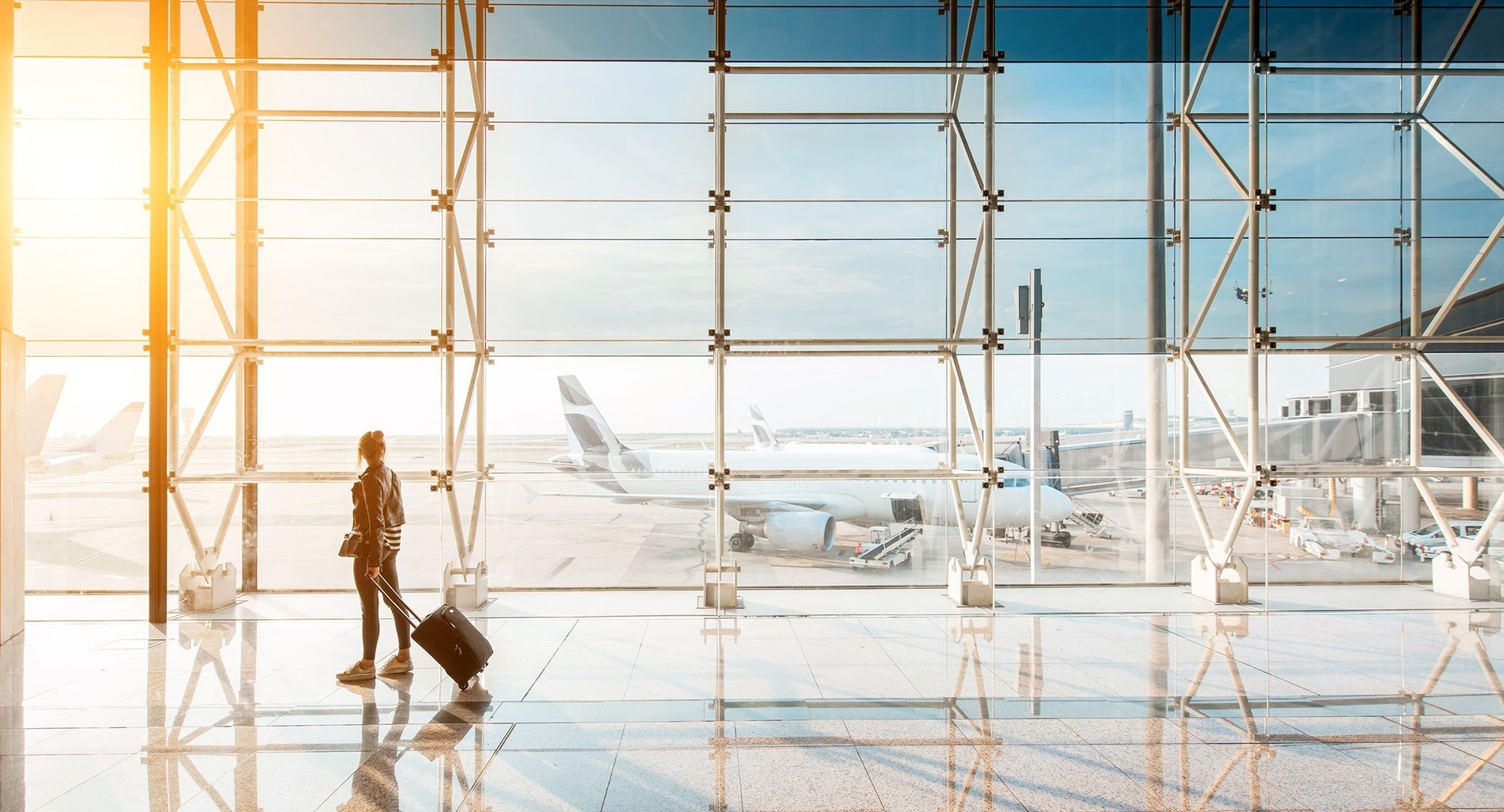 a woman walking down a hallway with a white suitcase