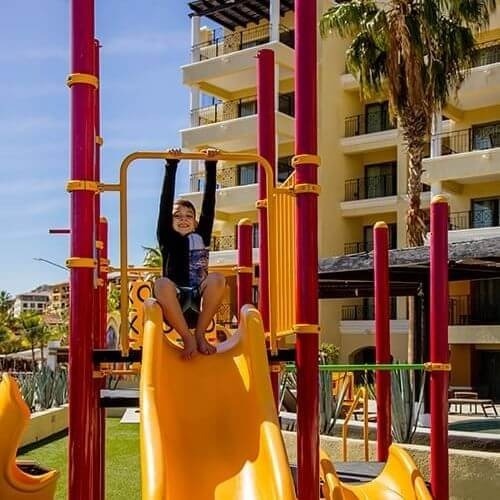 a young boy is playing on a slide at a playground .