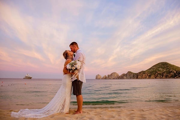 Pareja besandose el día de su boda en las playas de Los Cabos