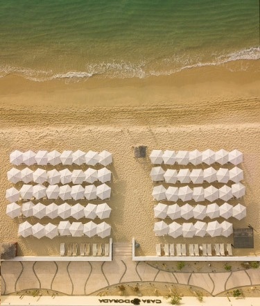 eine Luftaufnahme eines Strandes mit vielen weißen Regenschirmen