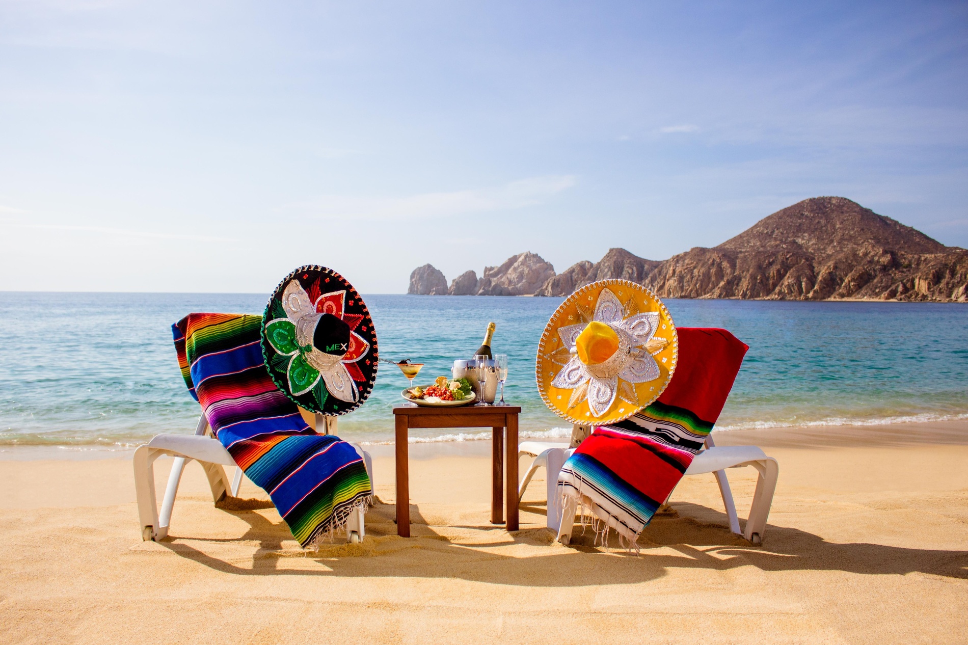 zwei mexikanische Hüte sitzen neben einem Tisch am Strand