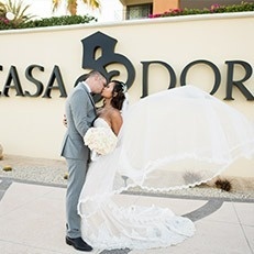 a bride and groom kissing in front of a casa dor sign