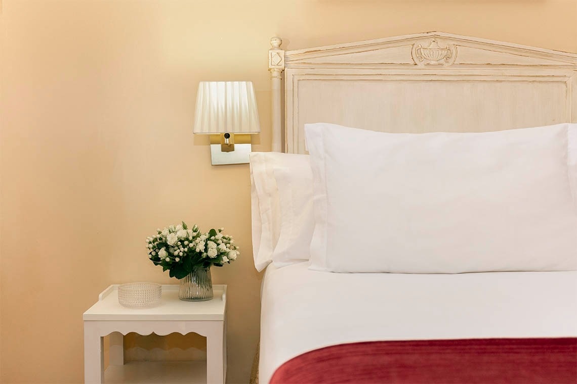 una cama con un jarrón de flores en la mesita de noche