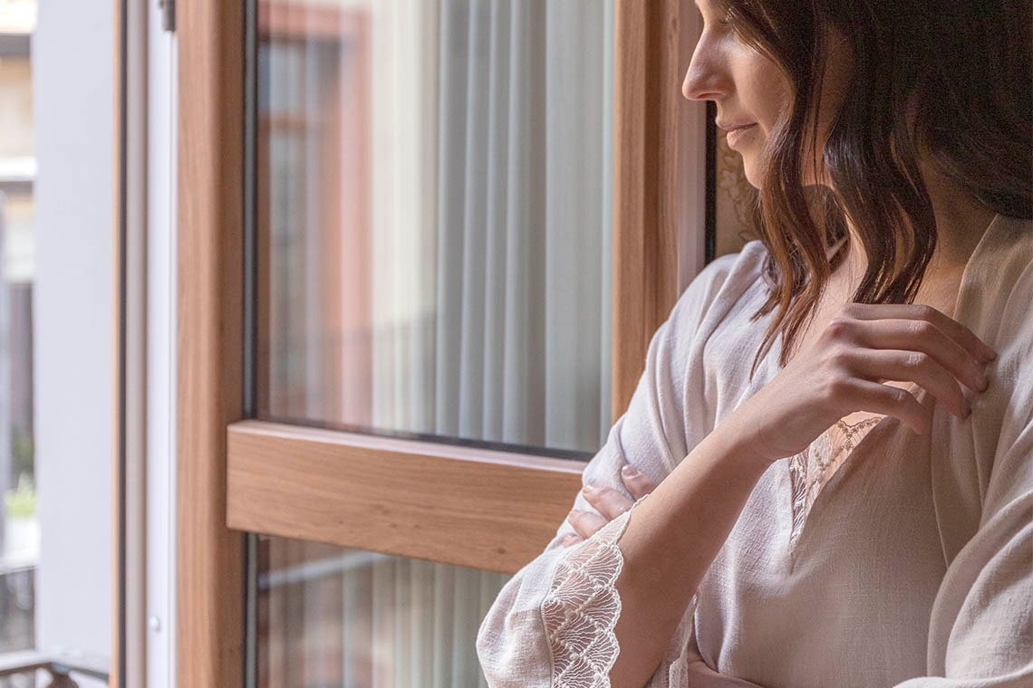 una mujer con una bata blanca mira por la ventana