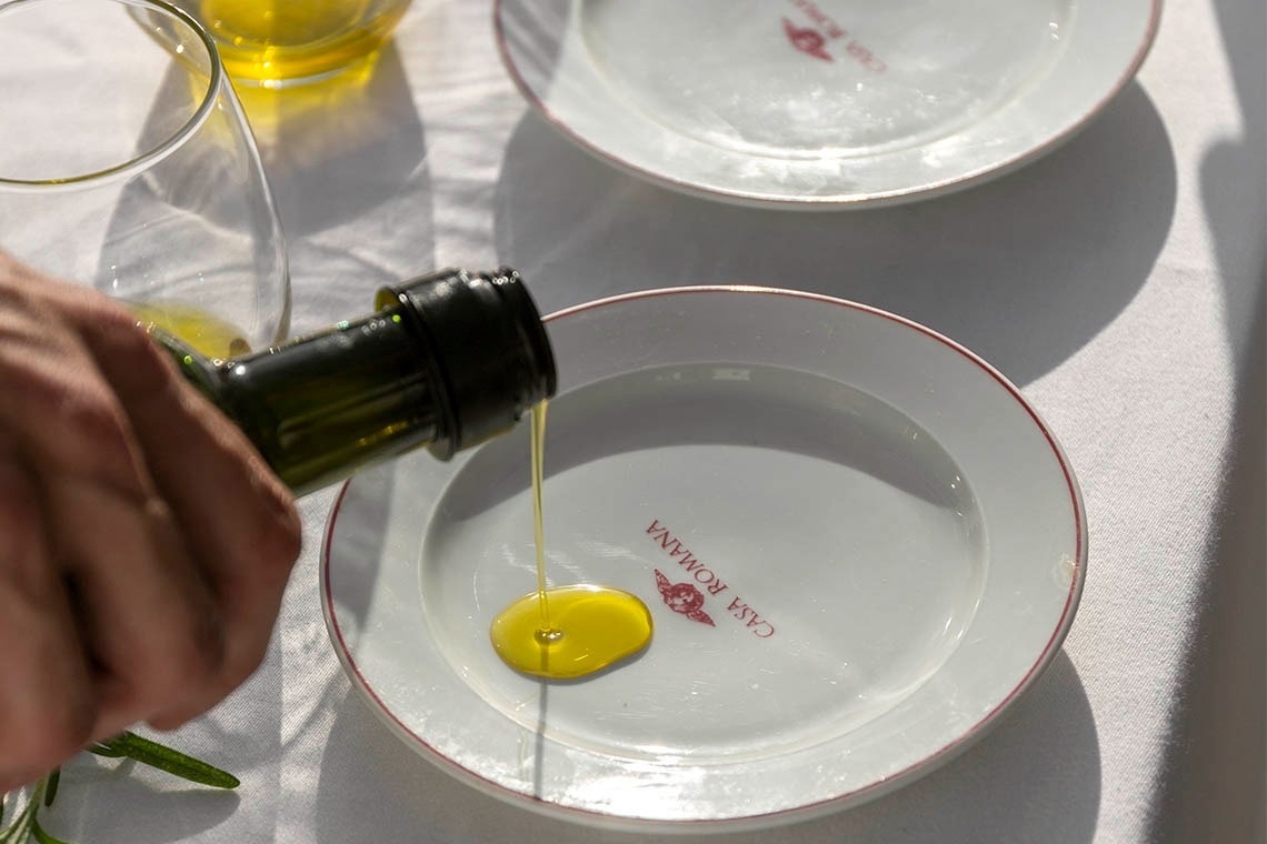 a person pouring oil on a white plate that says casa romana