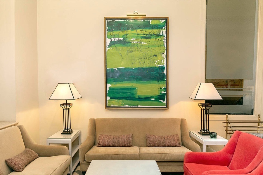 una sala de estar con sofás y lámparas y una pintura verde sobre la pared
