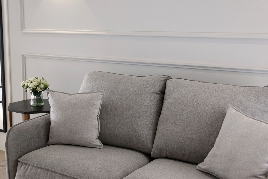 a couch with two pillows and a vase of flowers on it