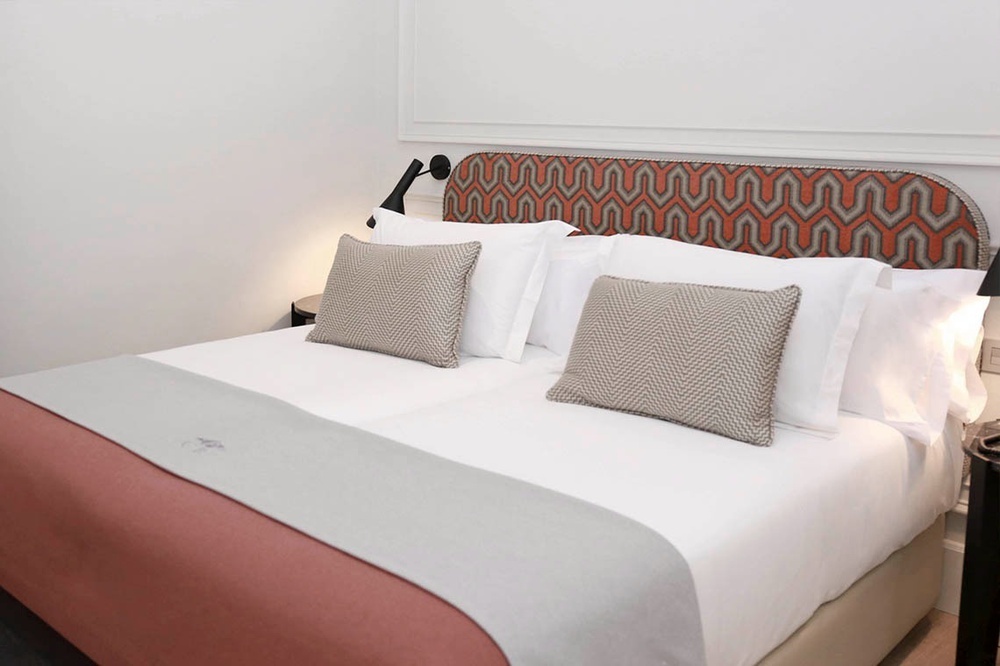 una cama con sábanas blancas y almohadas en una habitación de hotel