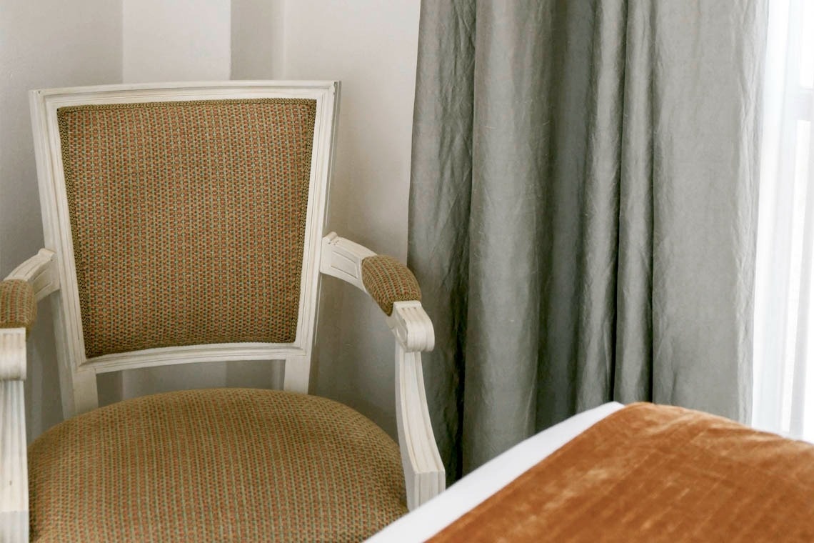 una silla está sentada junto a una cama y una ventana