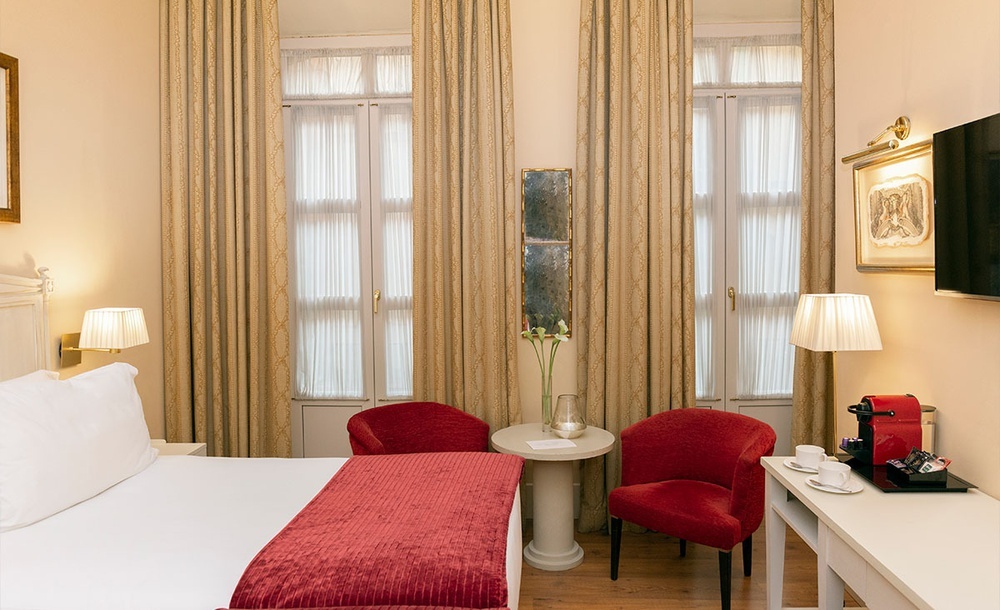 una habitación de hotel con una cama y dos sillas rojas