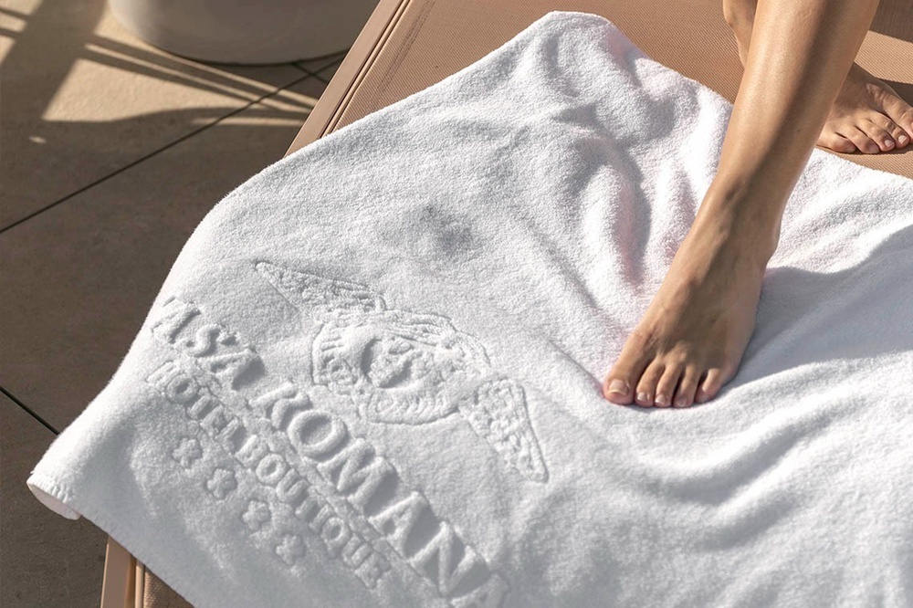 una persona acostada en una toalla blanca con el logotipo del hotel