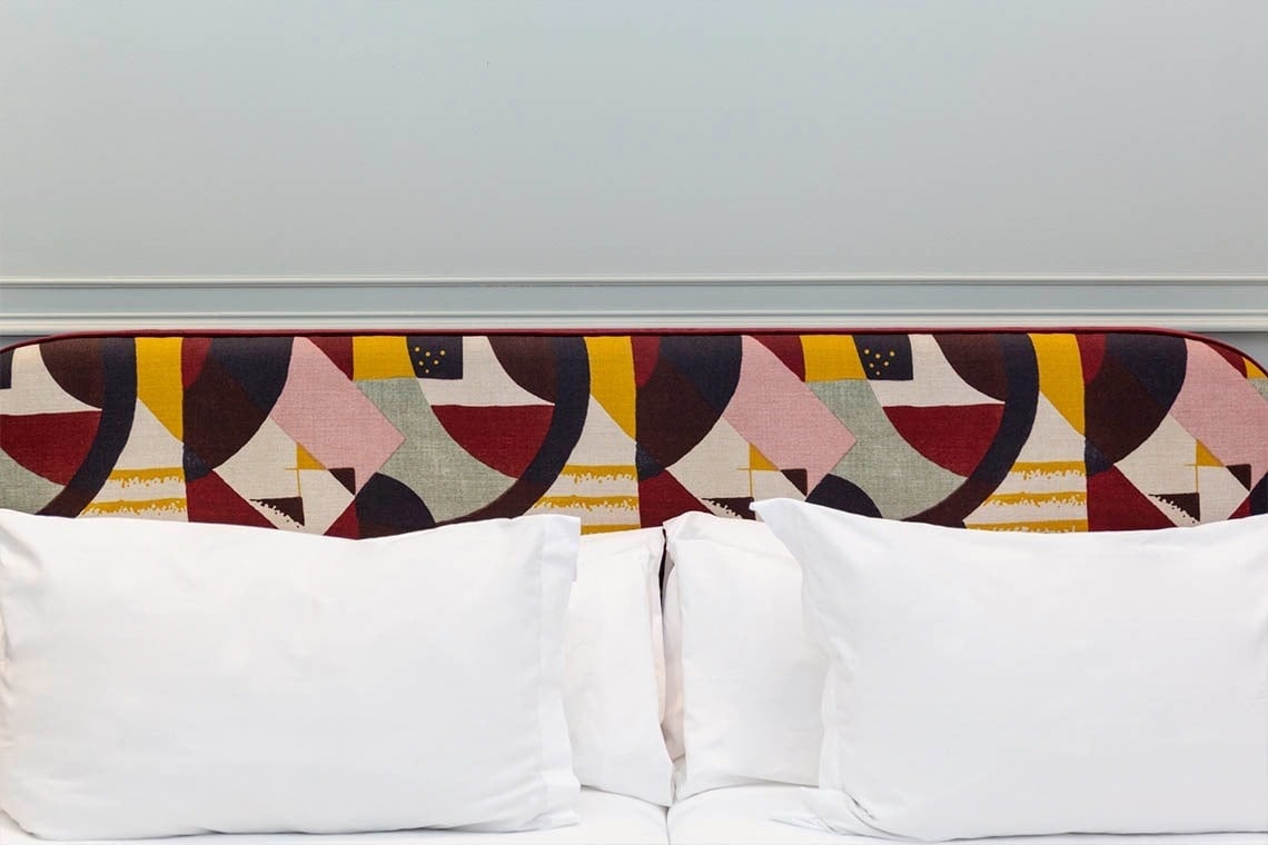 una cama con una cabecera colorida y almohadas blancas