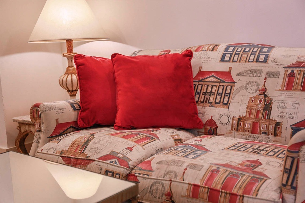 un sofá con un patrón de edificios y una almohada roja