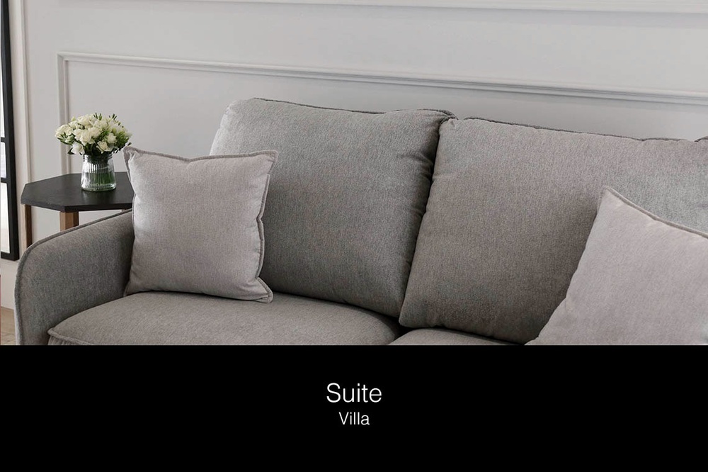 un sofá gris con almohadas y un jarrón de flores