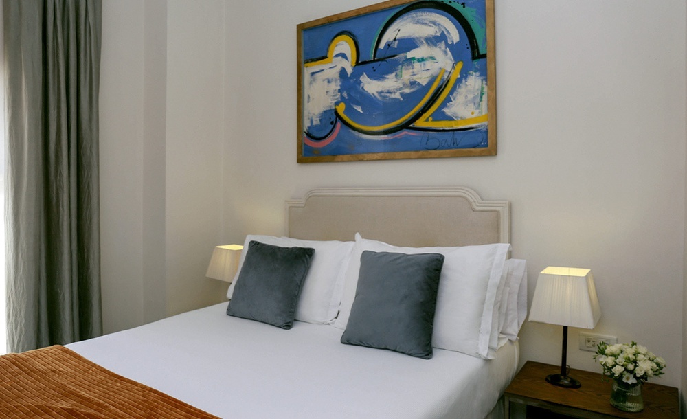 a bedroom with a painting on the wall above the bed