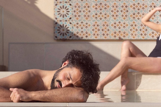 un hombre sin camisa está acostado en el borde de una piscina
