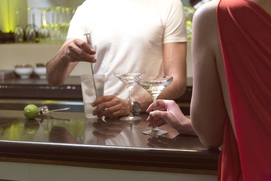 una mujer sostiene una copa de martini mientras un hombre prepara un cóctel