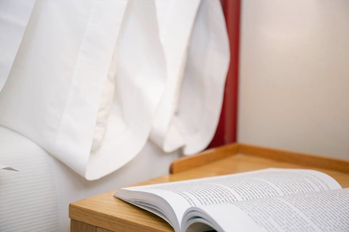 un libro está abierto en una mesita de noche junto a una cama