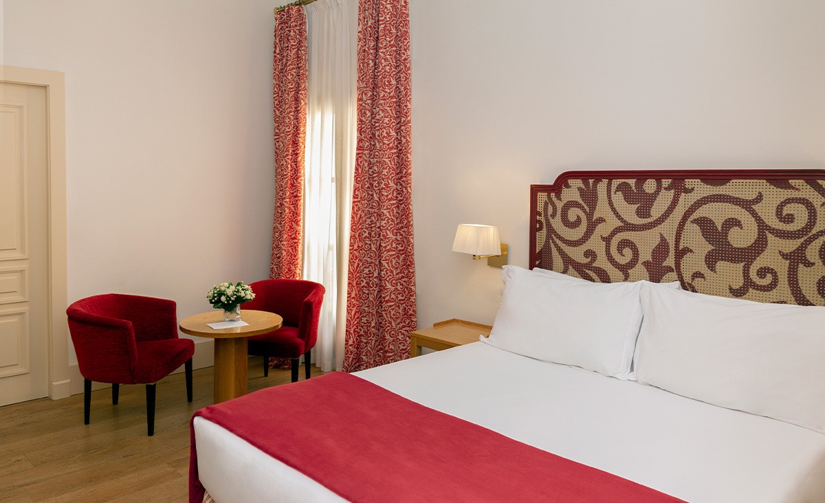 una habitación con una cama y dos sillas rojas