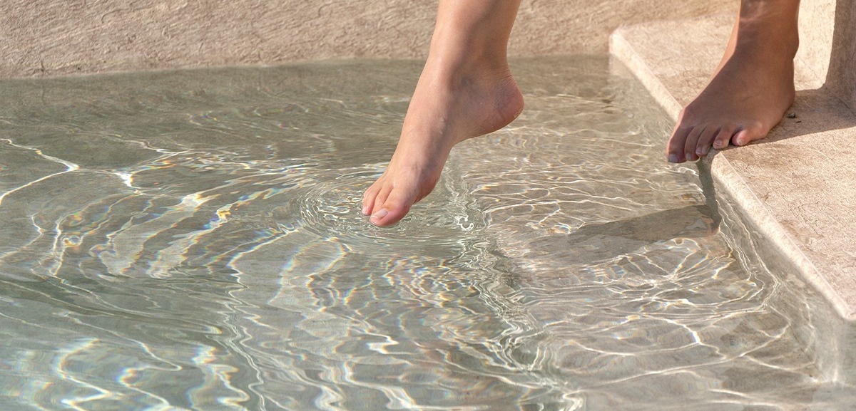 los pies de una persona están en los escalones de una piscina