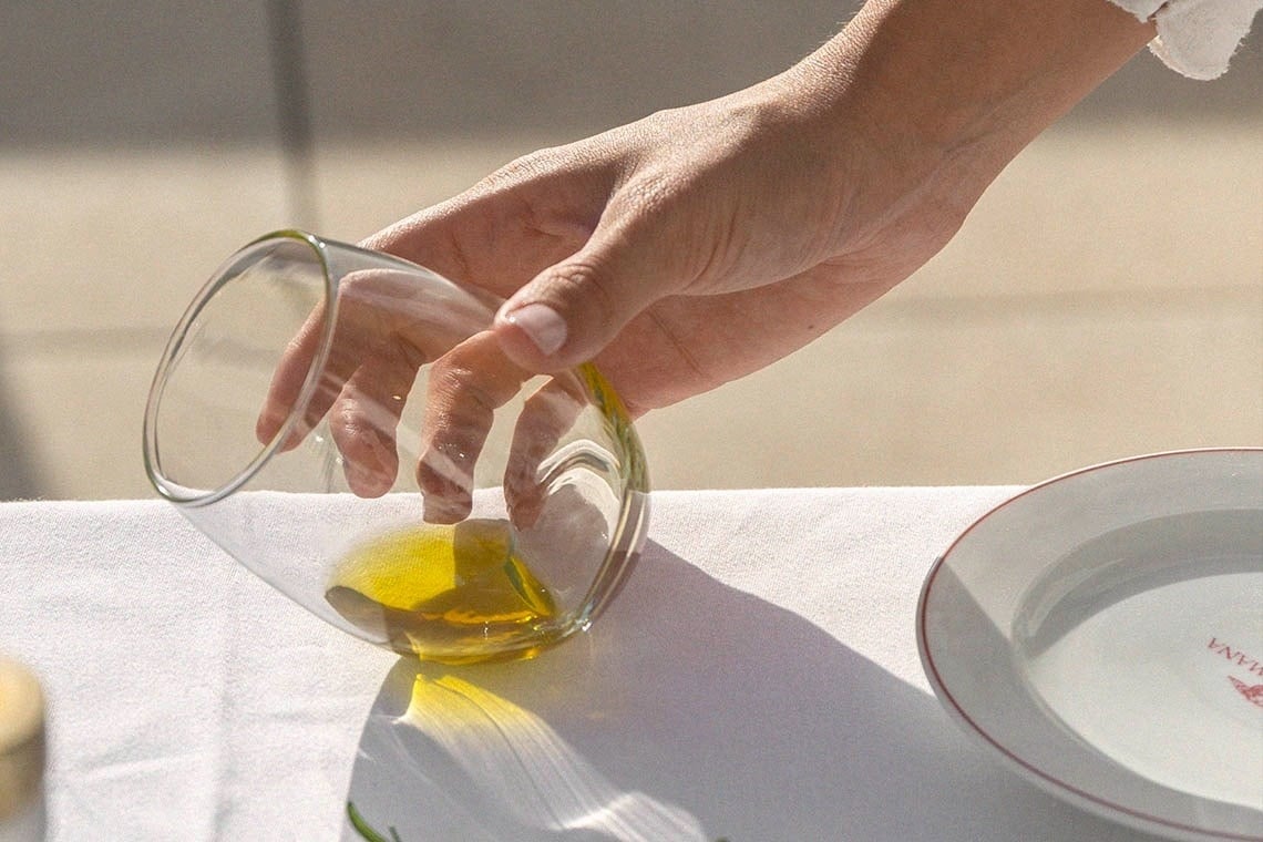 a person is pouring olive oil into a glass