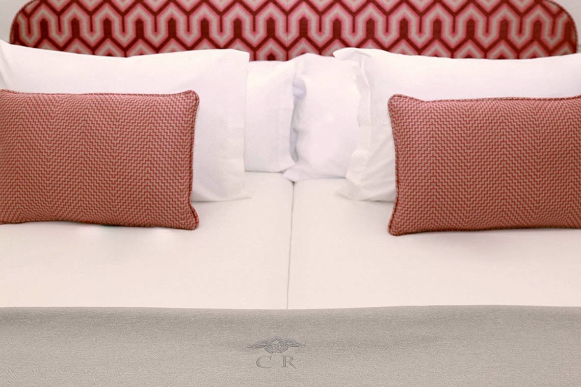 a bed with pillows and a blanket that says cr on it